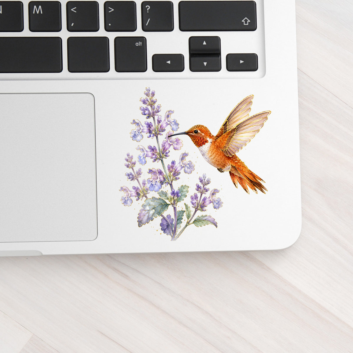 Rufous Hummingbird Lavender UV DTF sticker applied to a silver laptop beside the keyboard