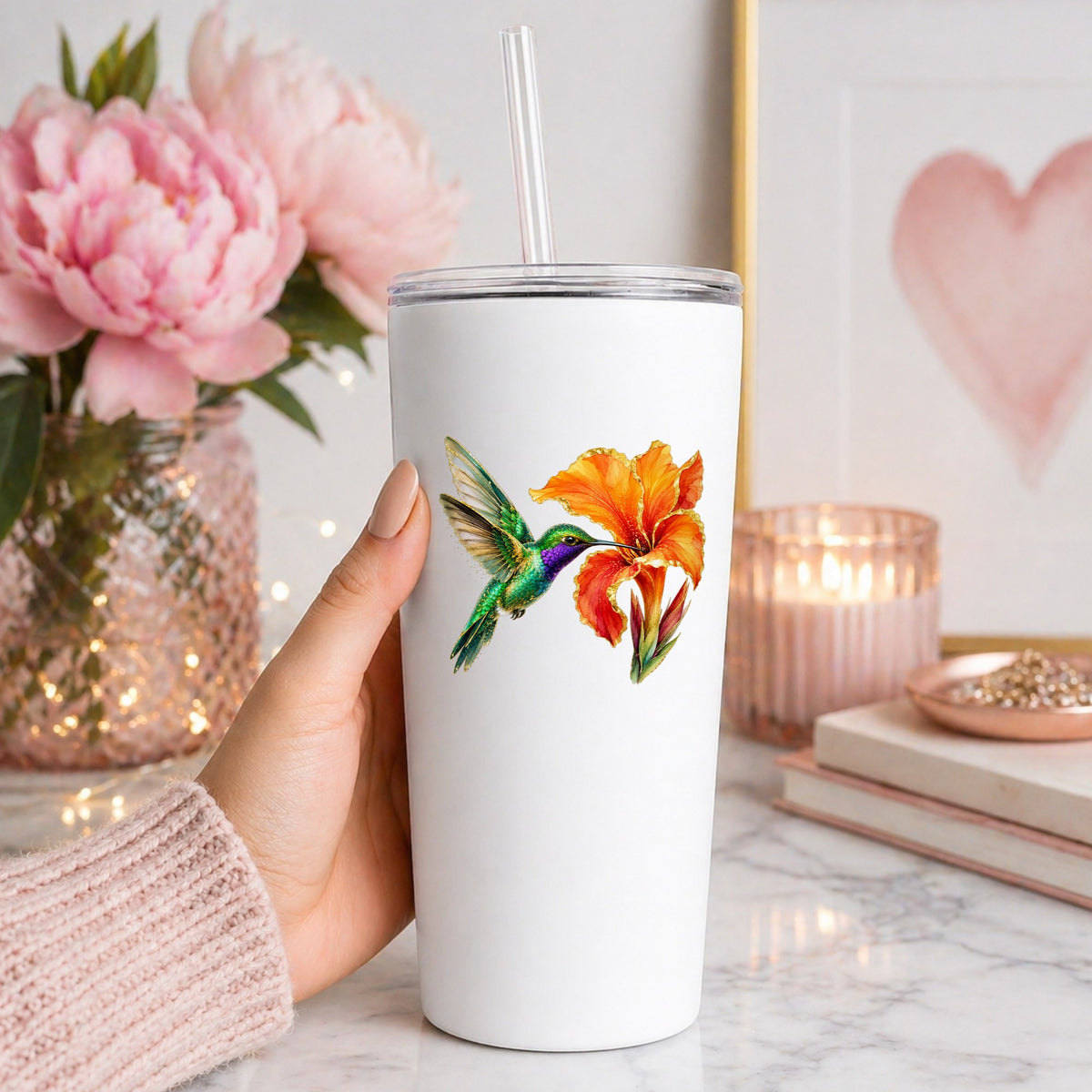 Hummingbird Orange Canna Lily UV DTF sticker applied to a white straw tumbler beside pink peonies