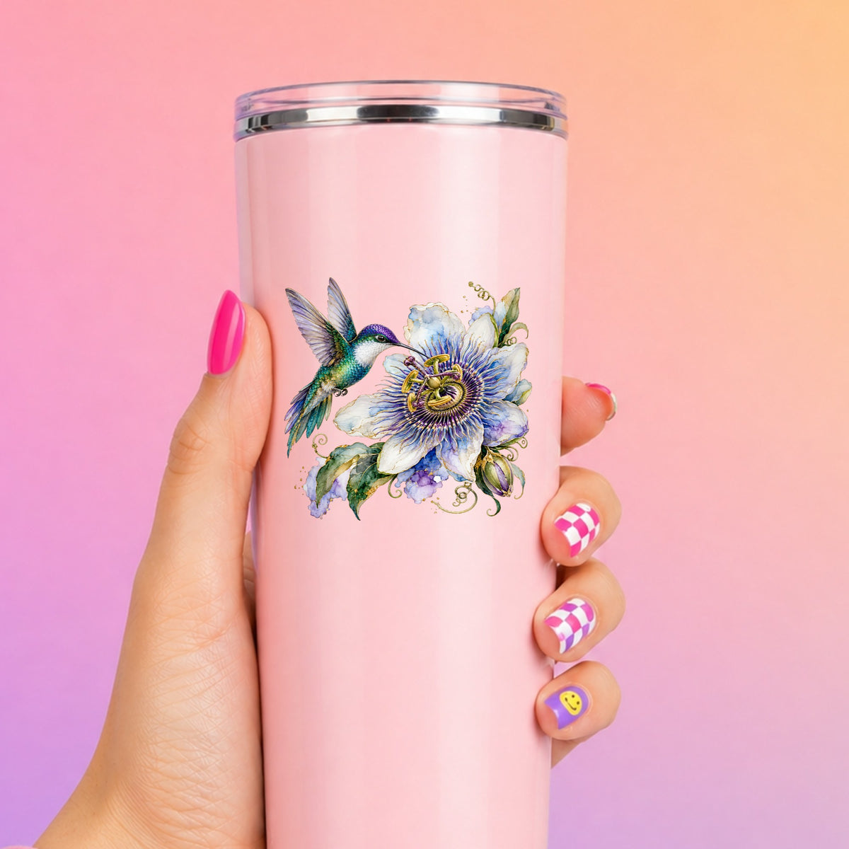 Hummingbird Passion Flower UV DTF sticker applied to a tall pink tumbler on a pink and orange background