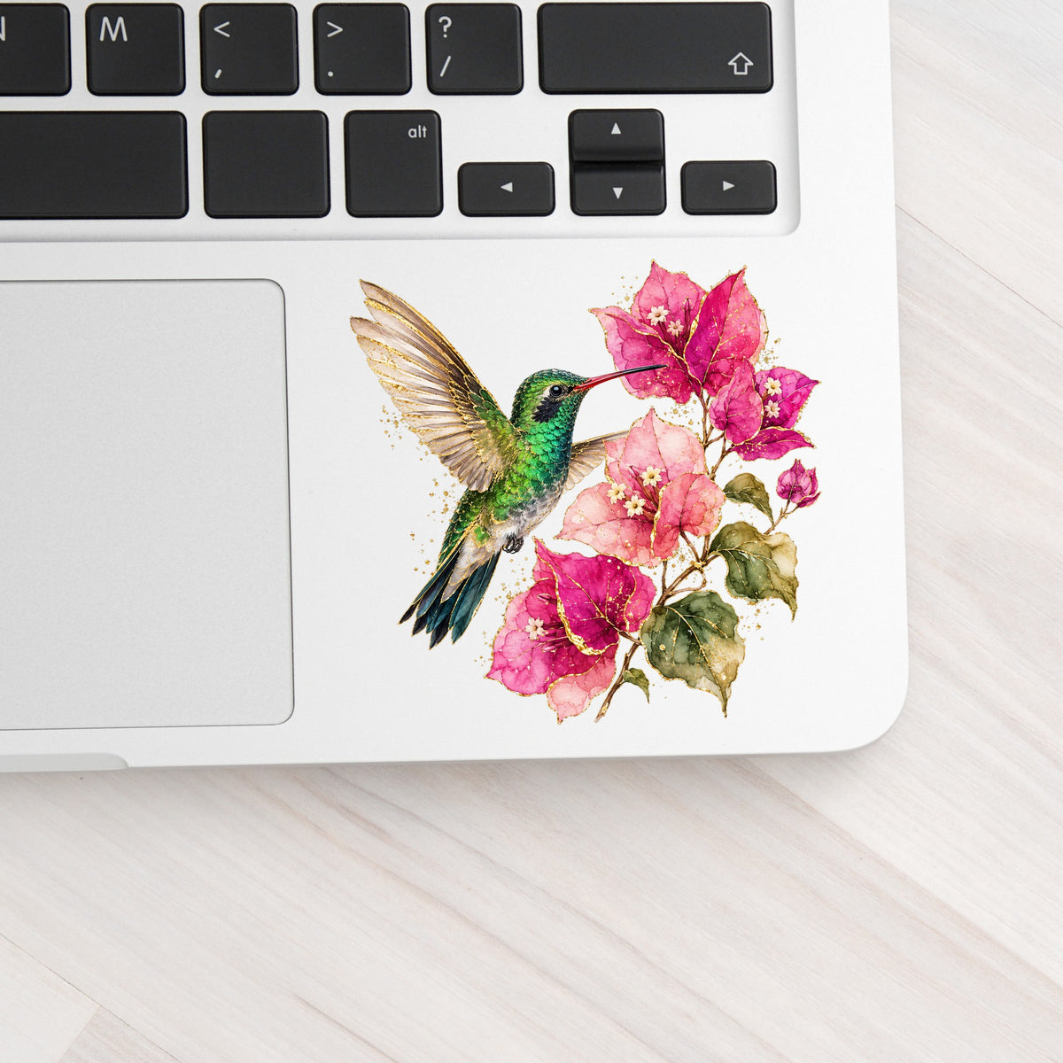Hummingbird Pink Bougainvillea UV DTF sticker applied to a silver laptop beside the keyboard