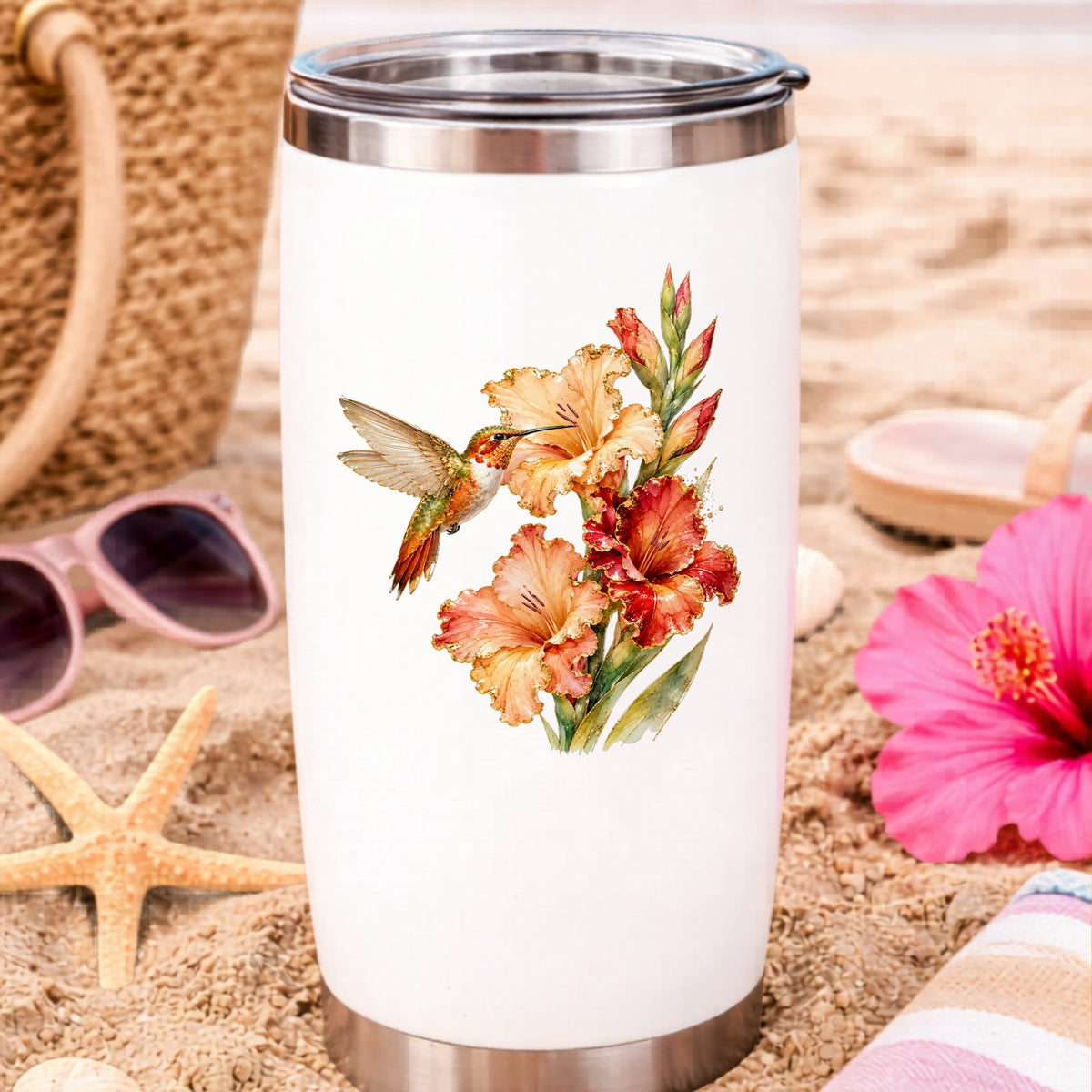 Hummingbird Peach Gladiolus UV DTF sticker applied to a white travel tumbler on beach sand