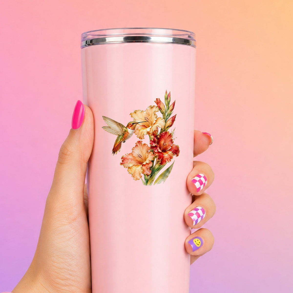 Hummingbird Peach Gladiolus UV DTF sticker applied to a tall pink tumbler on a pink and orange background