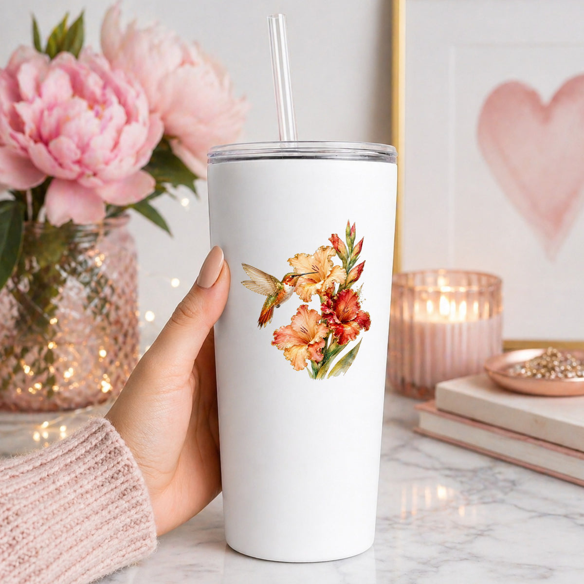 Hummingbird Peach Gladiolus UV DTF sticker applied to a white straw tumbler beside pink peonies