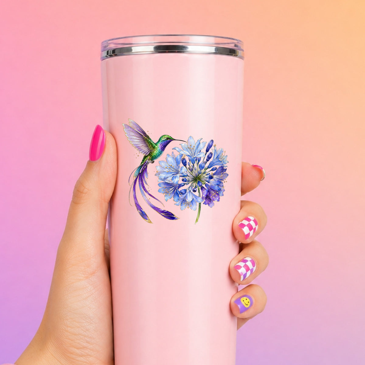 Hummingbird Blue Agapanthus UV DTF sticker applied to a tall pink tumbler on a pink and orange background