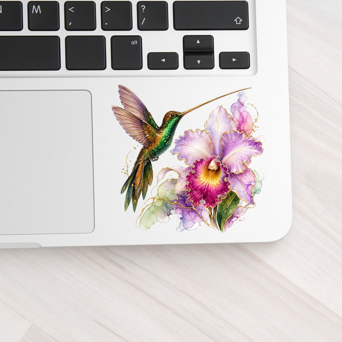 Hummingbird Purple Orchid UV DTF sticker applied to a silver laptop beside the keyboard
