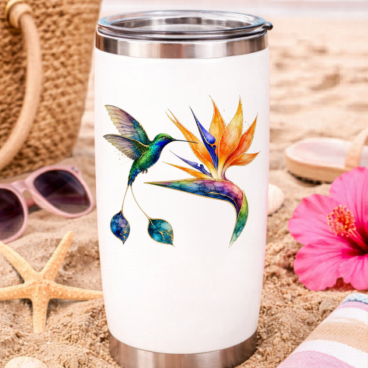 Hummingbird Bird Of Paradise Flower UV DTF sticker applied to a white travel tumbler on beach sand