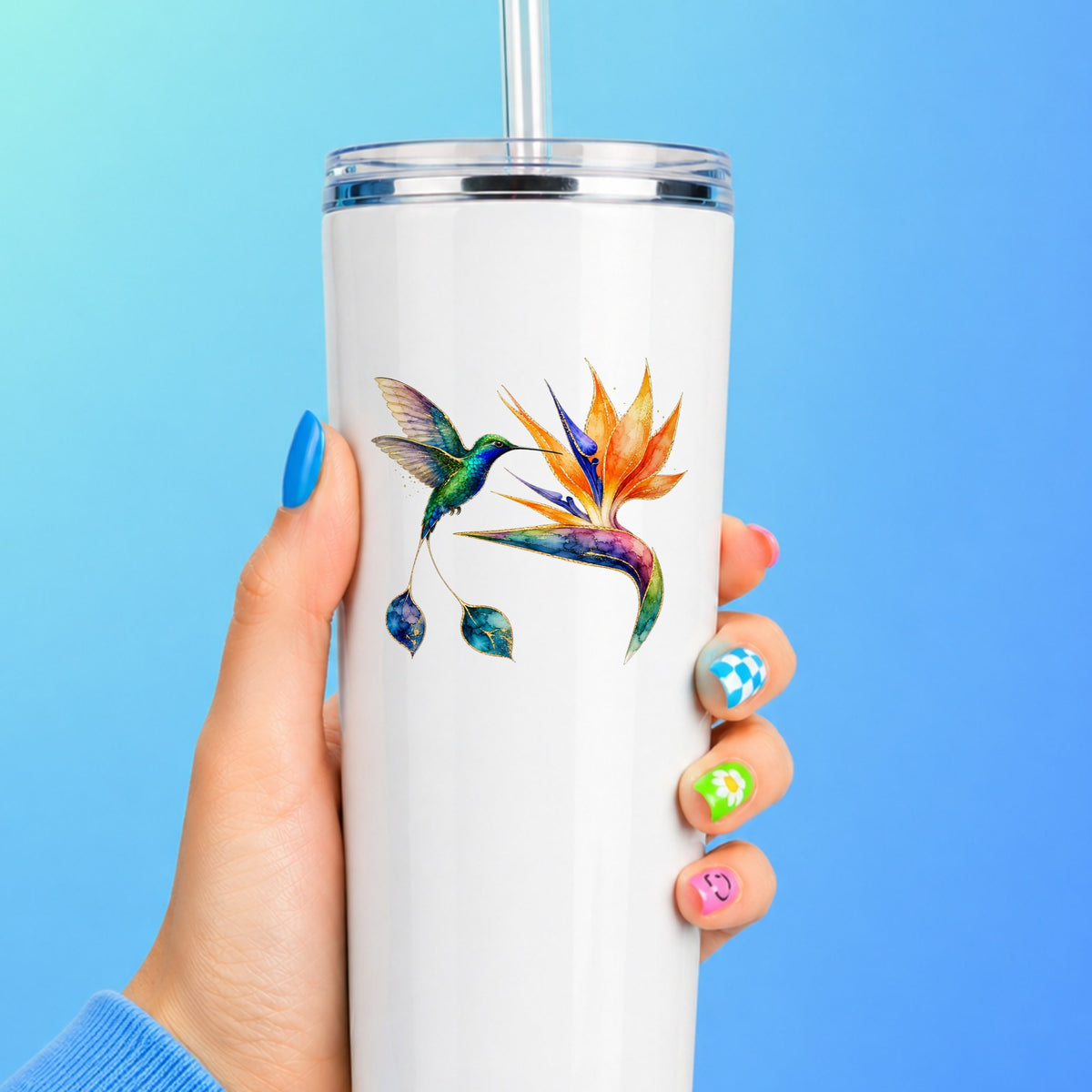 Hummingbird Bird Of Paradise Flower UV DTF sticker applied to a white straw tumbler on a blue background