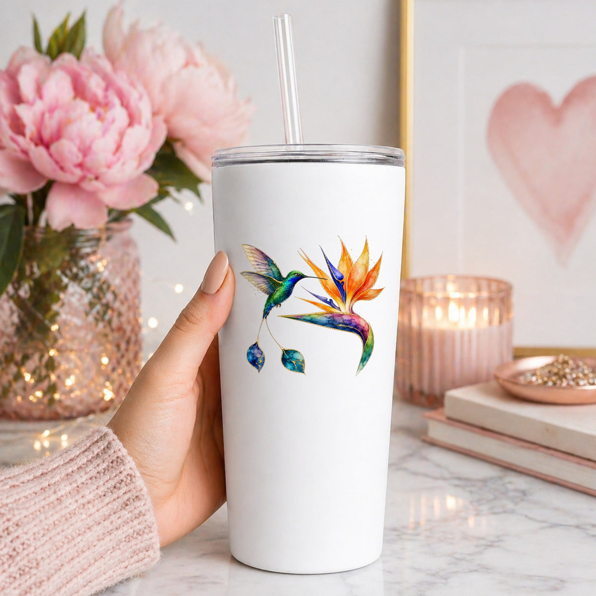 Hummingbird Bird Of Paradise Flower UV DTF sticker applied to a white straw tumbler beside pink peonies