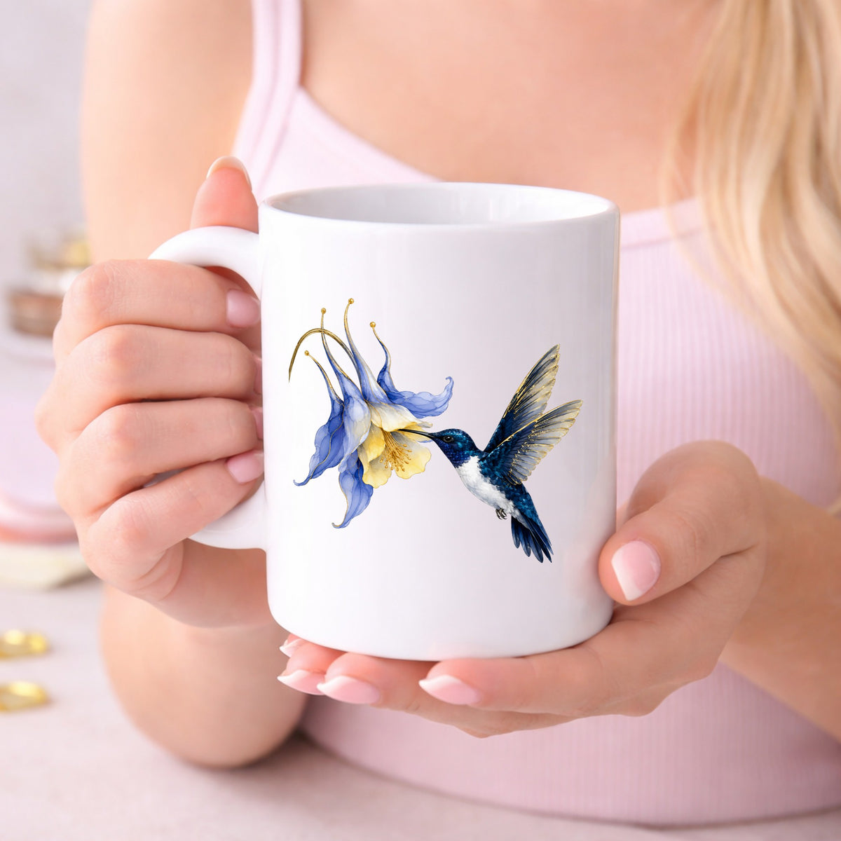 Navy Hummingbird Blue Columbine UV DTF sticker applied to a white coffee mug held in both hands