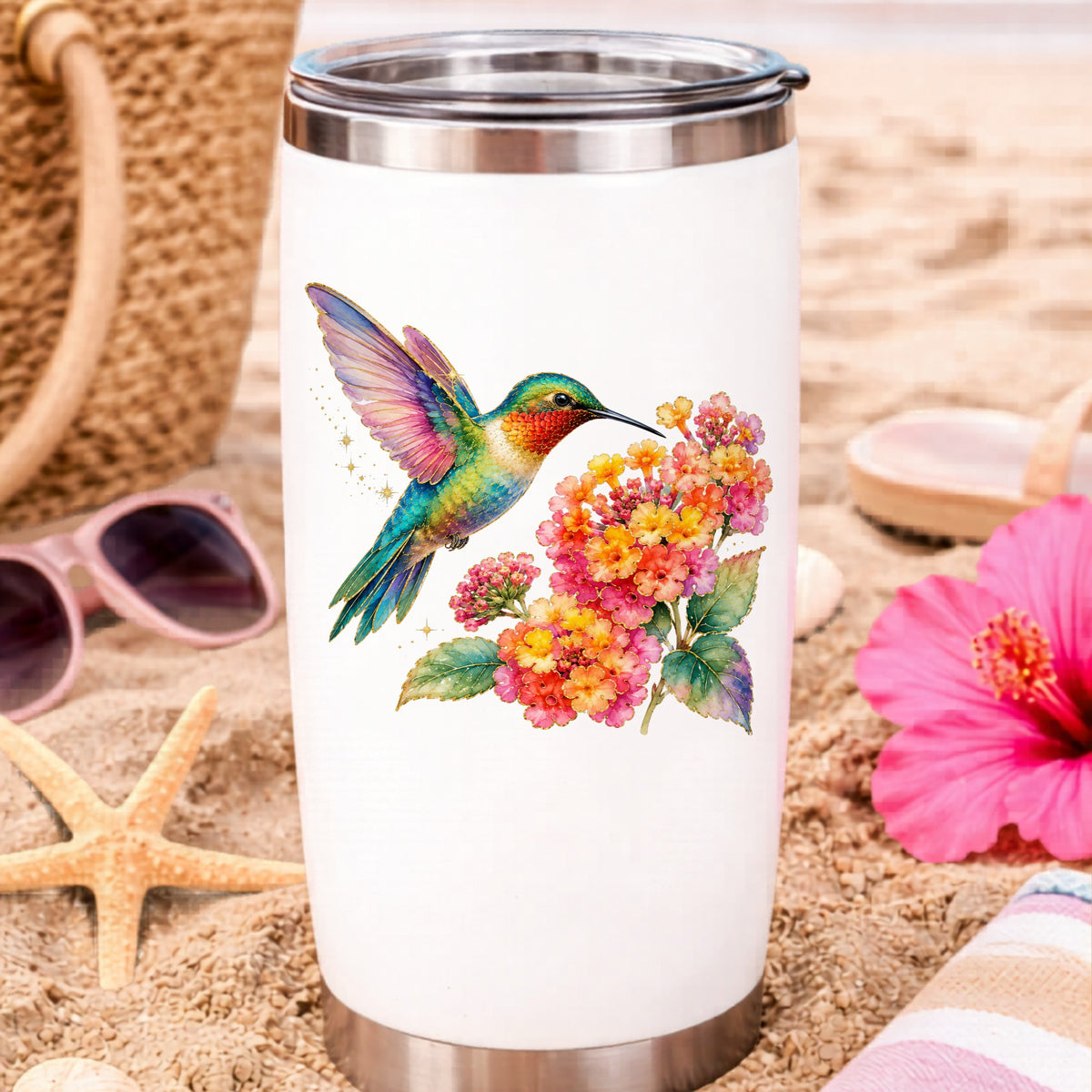 Rainbow Hummingbird Lantana UV DTF sticker applied to a white travel tumbler on beach sand