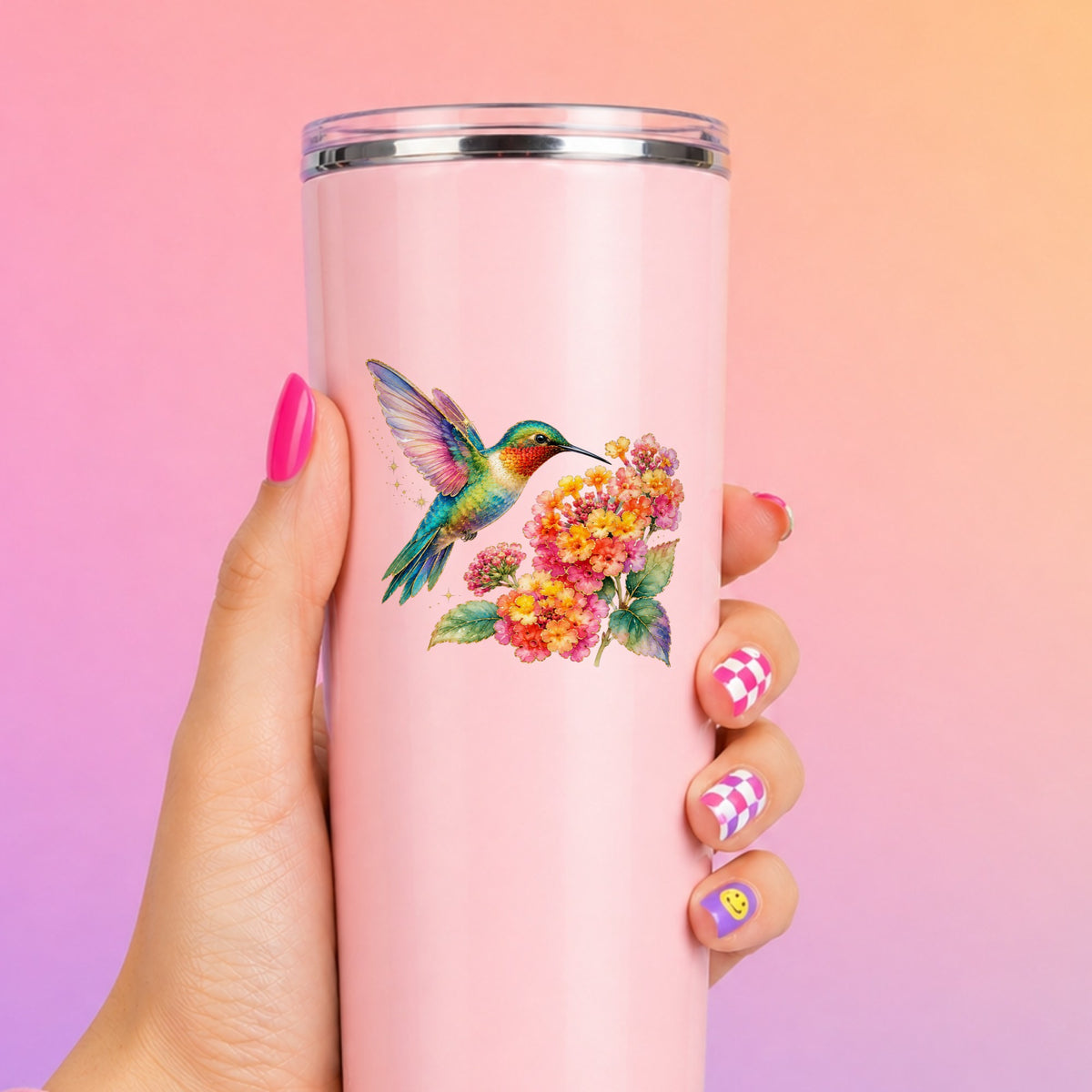 Rainbow Hummingbird Lantana UV DTF sticker applied to a tall pink tumbler on a pink and orange background