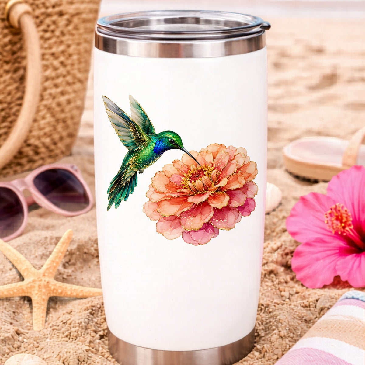 Hummingbird Coral Zinnia UV DTF sticker applied to a white travel tumbler on beach sand