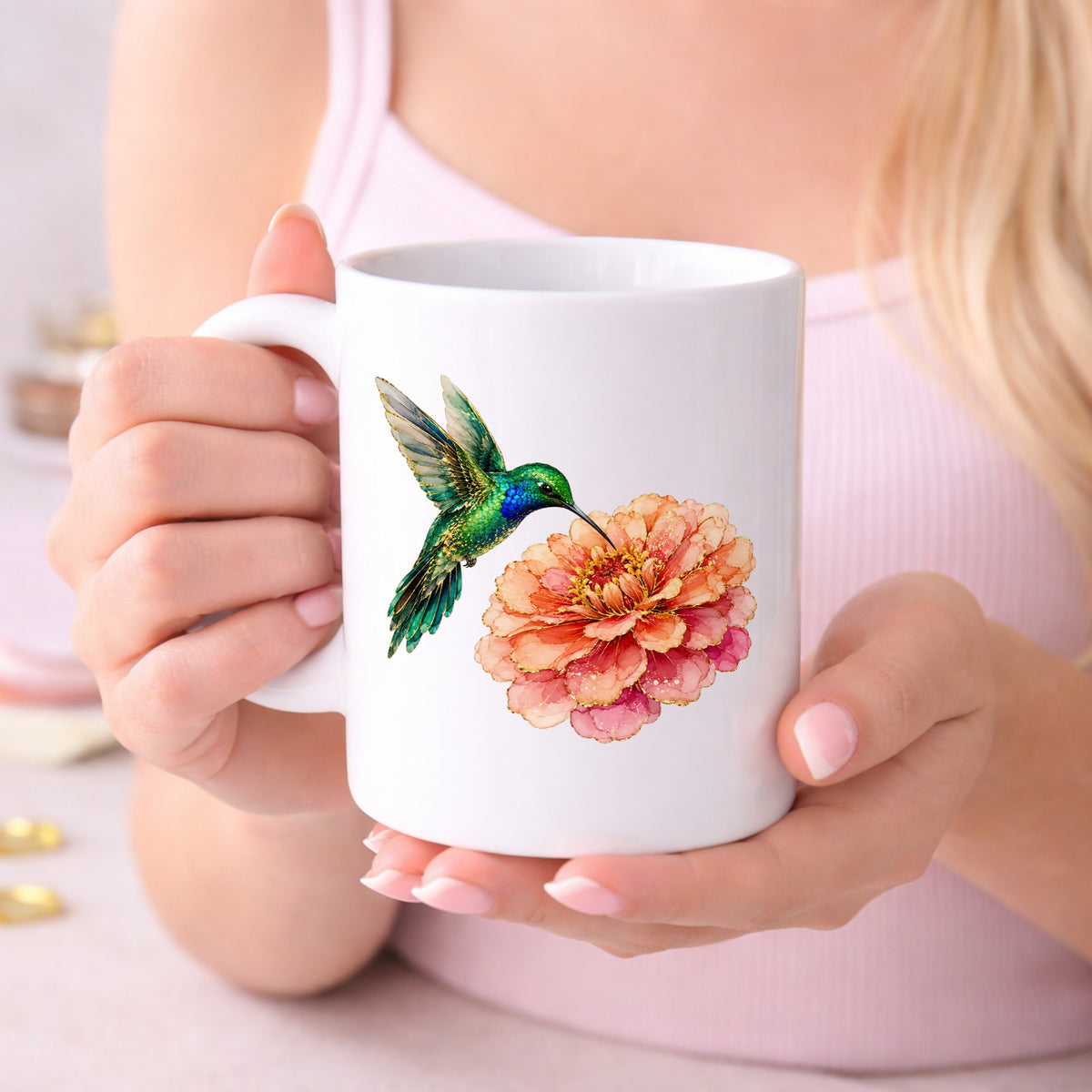 Hummingbird Coral Zinnia UV DTF sticker applied to a white coffee mug held in both hands