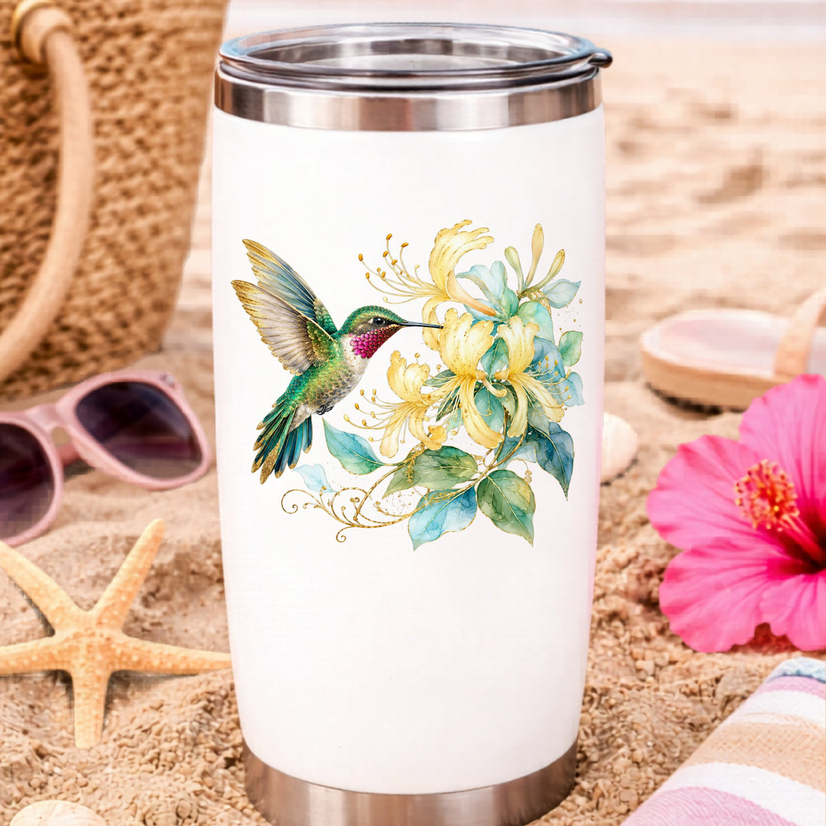 Hummingbird Yellow Honeysuckle UV DTF sticker applied to a white travel tumbler on beach sand