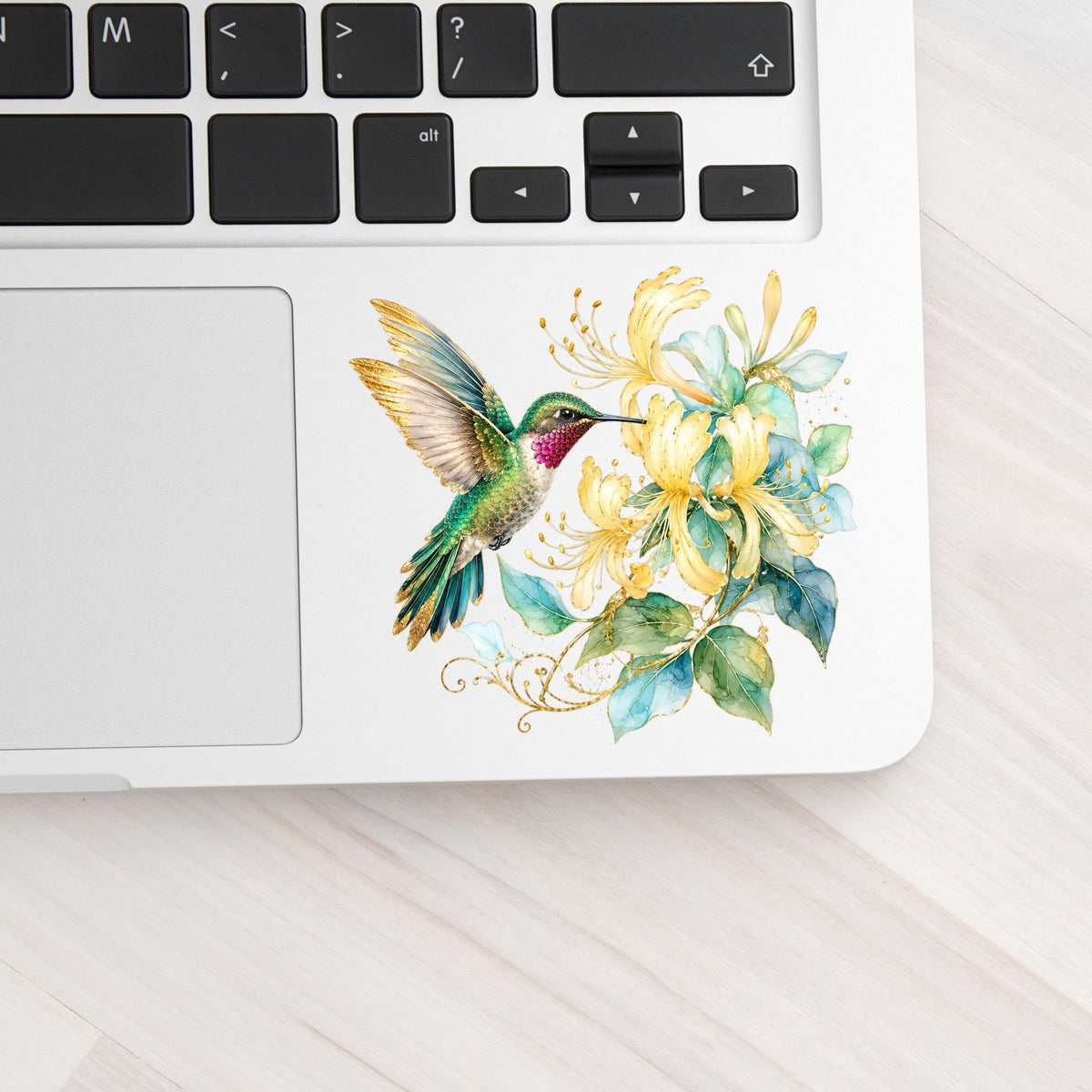 Hummingbird Yellow Honeysuckle UV DTF sticker applied to a silver laptop beside the keyboard