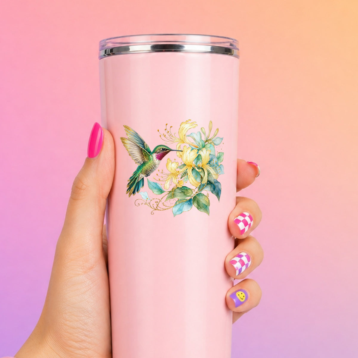 Hummingbird Yellow Honeysuckle UV DTF sticker applied to a tall pink tumbler on a pink and orange background