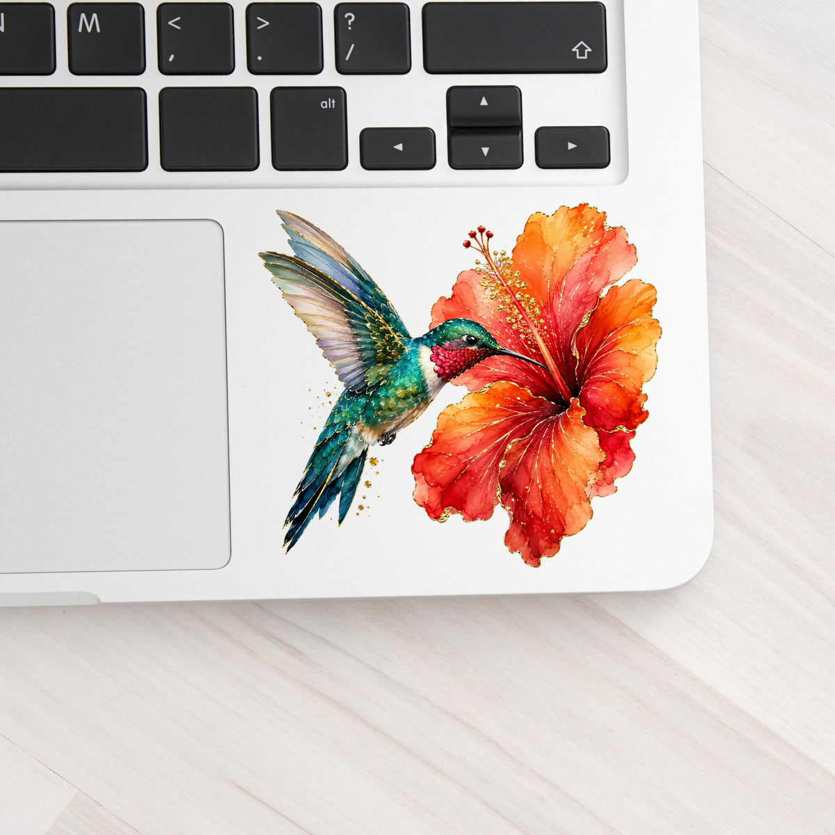 Hummingbird Red Hibiscus UV DTF sticker applied to a silver laptop beside the keyboard