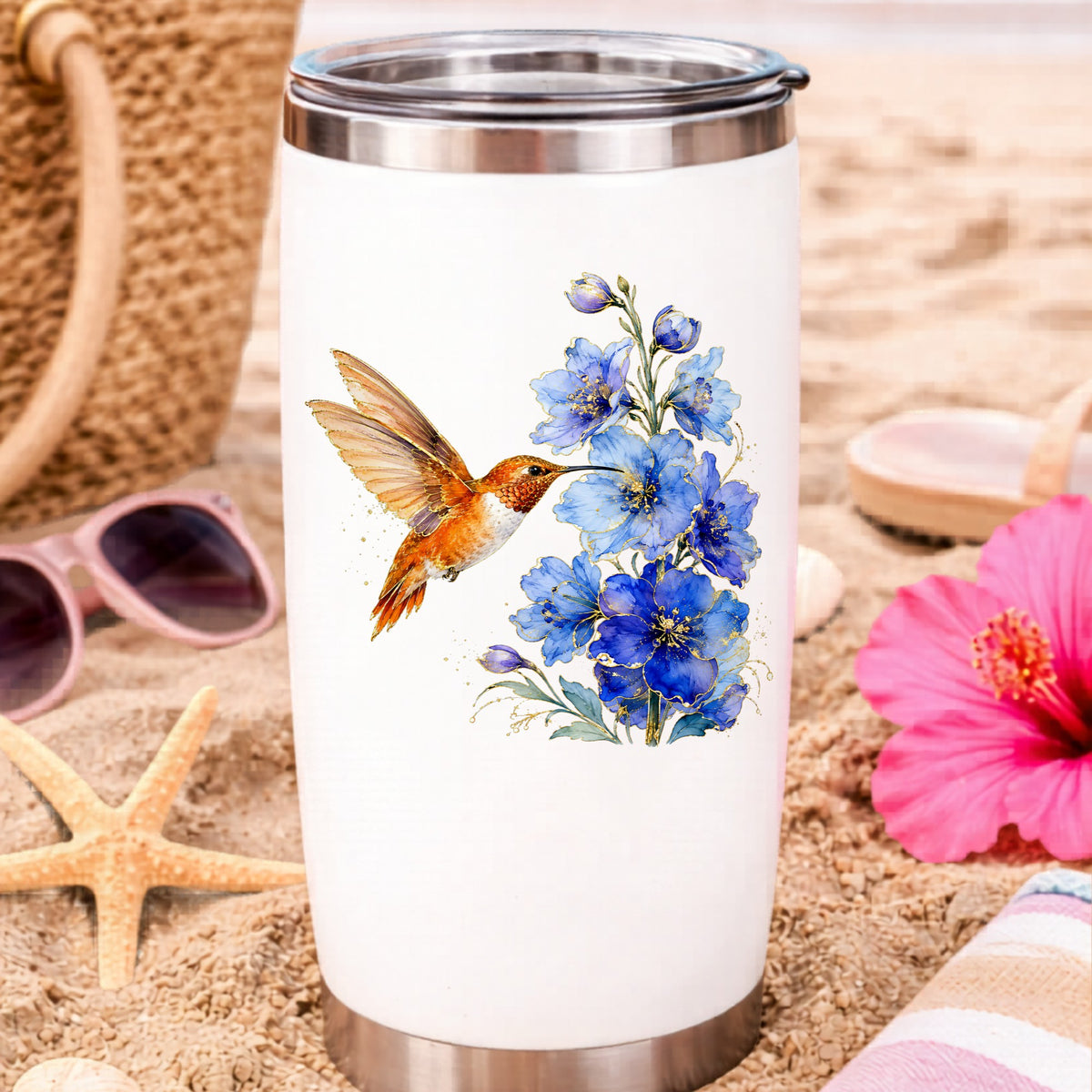Rufous Hummingbird Blue Delphinium UV DTF sticker applied to a white travel tumbler on beach sand