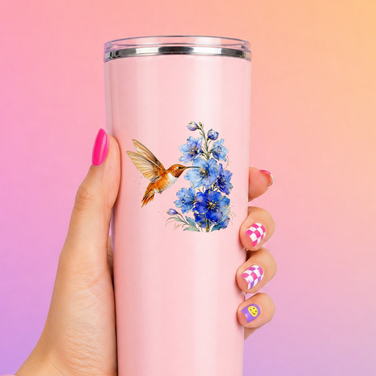 Rufous Hummingbird Blue Delphinium UV DTF sticker applied to a tall pink tumbler on a pink and orange background