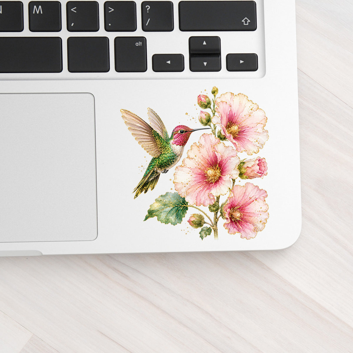 Hummingbird Pink Hollyhock UV DTF sticker applied to a silver laptop beside the keyboard