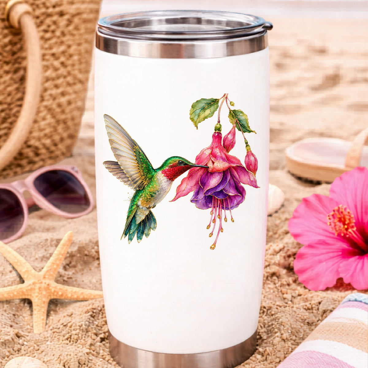 Hummingbird Fuchsia Flower UV DTF sticker applied to a white travel tumbler on beach sand