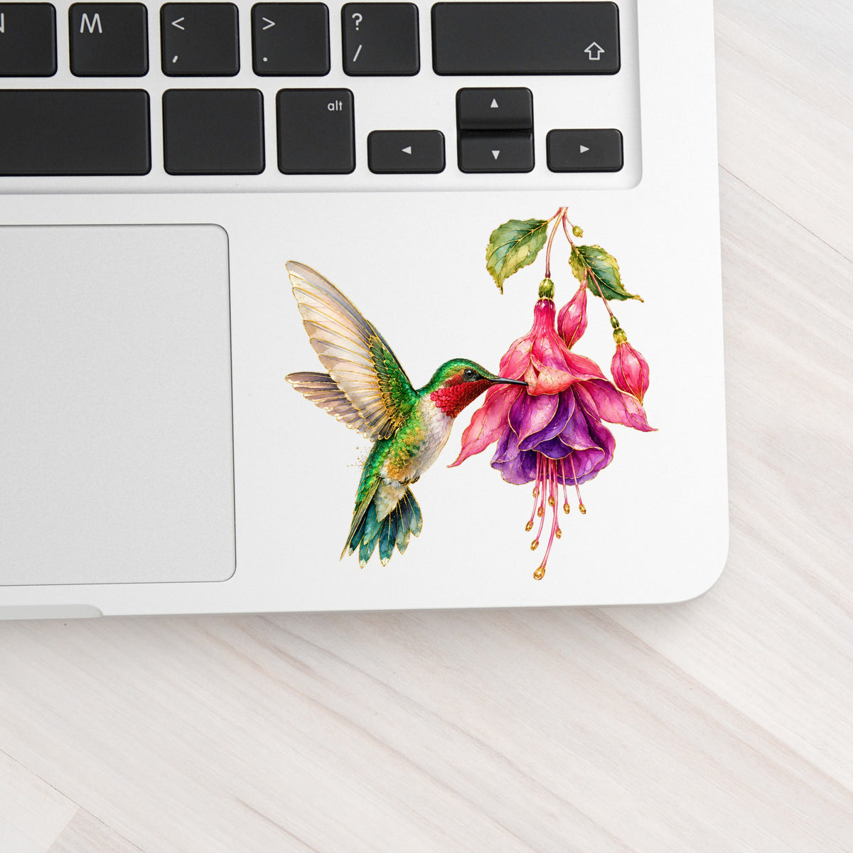 Hummingbird Fuchsia Flower UV DTF sticker applied to a silver laptop beside the keyboard