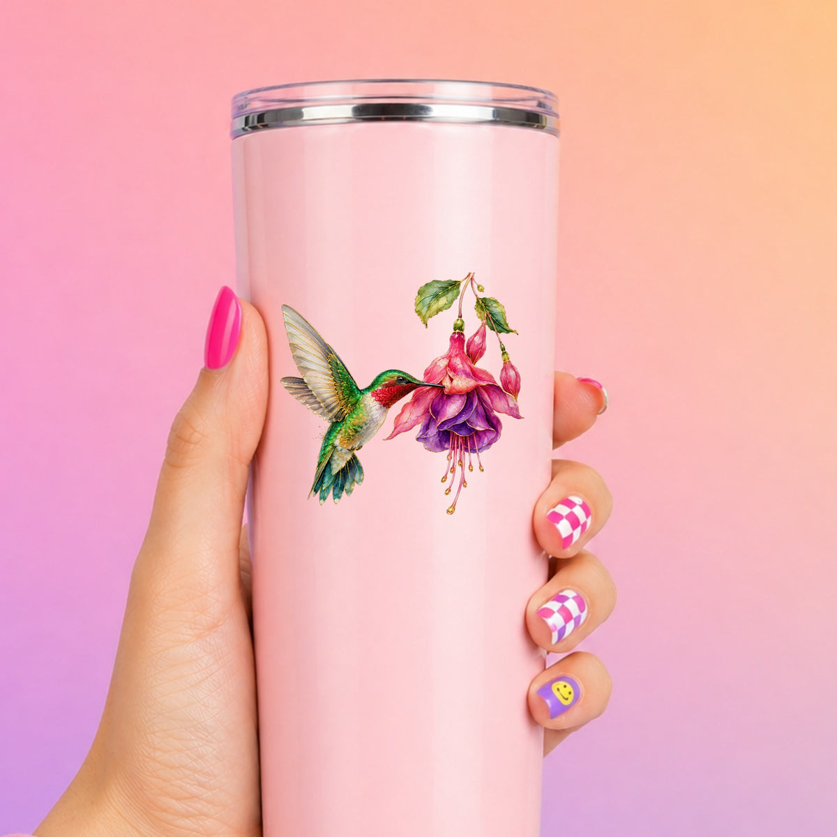 Hummingbird Fuchsia Flower UV DTF sticker applied to a tall pink tumbler on a pink and orange background