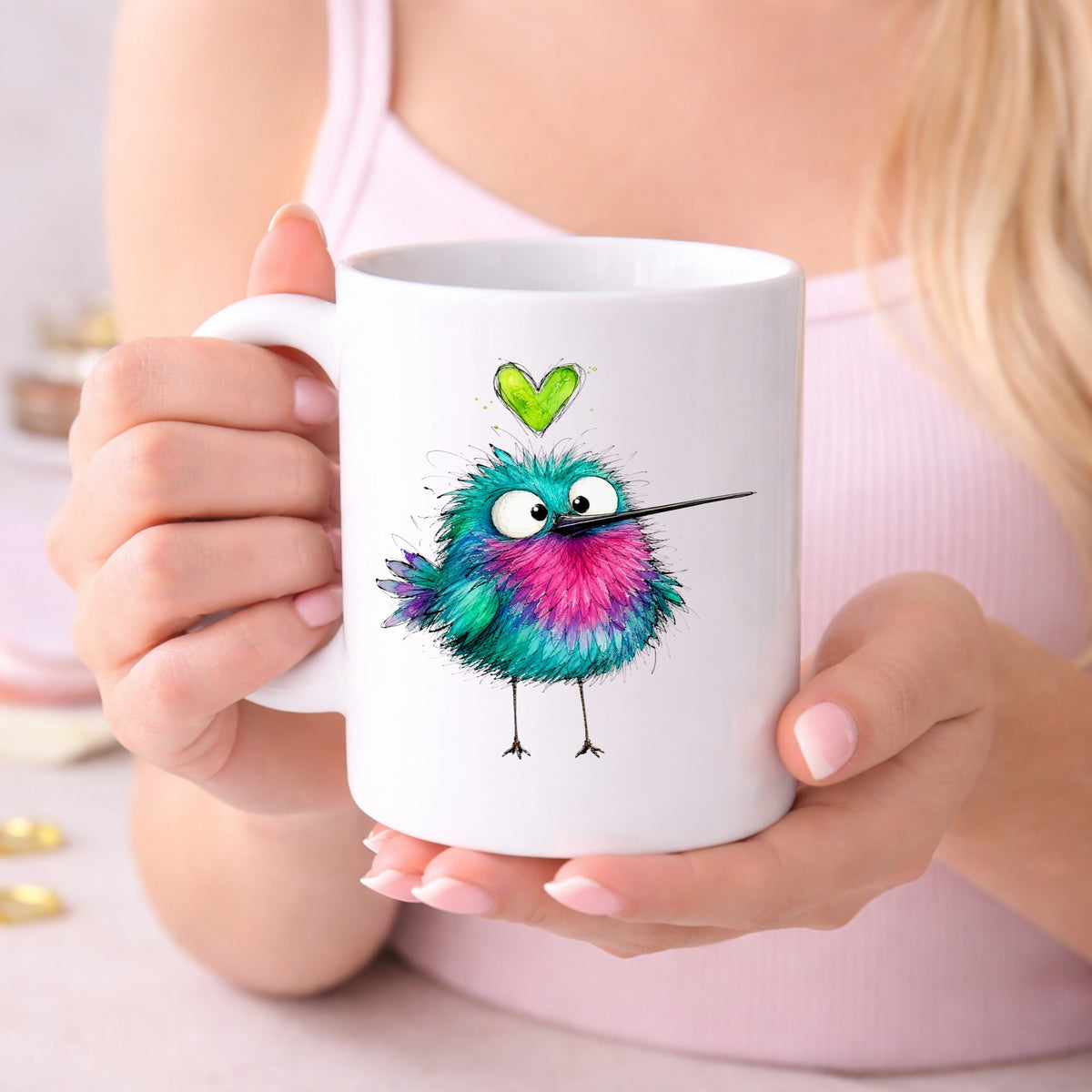 Fluffy Teal Pink Hummingbird UV DTF sticker applied to a white coffee mug held in both hands