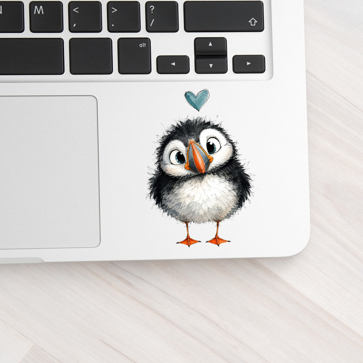 Funny Puffin UV DTF sticker applied to a silver laptop beside the keyboard