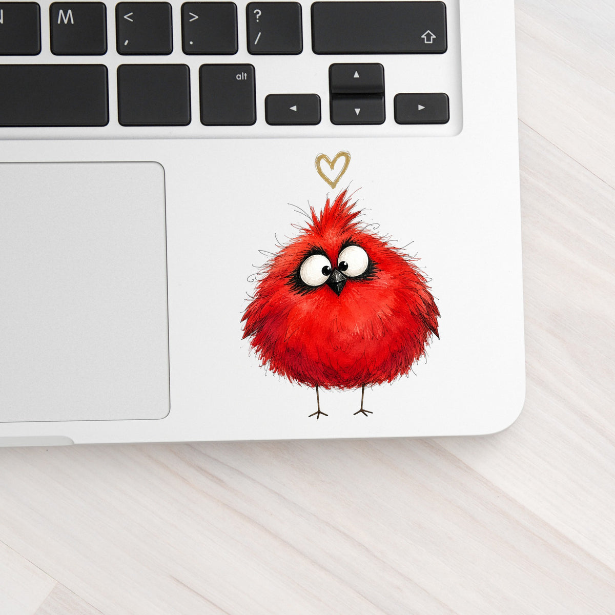 Fluffy Red Cardinal UV DTF sticker applied to a silver laptop beside the keyboard