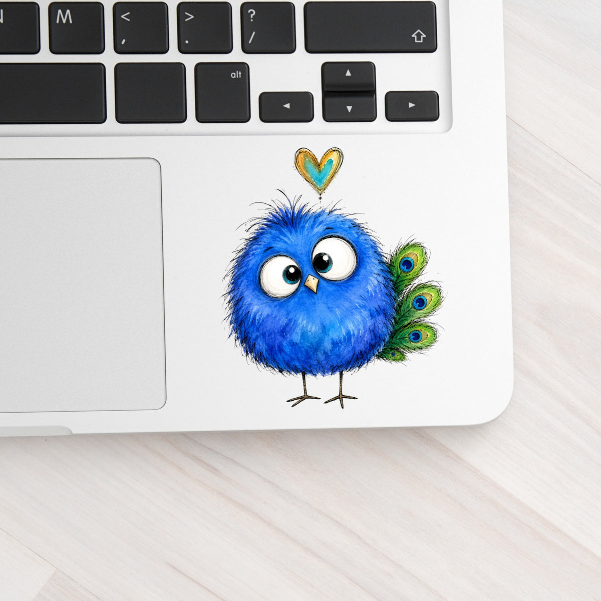 Funny Blue Peacock UV DTF sticker applied to a silver laptop beside the keyboard