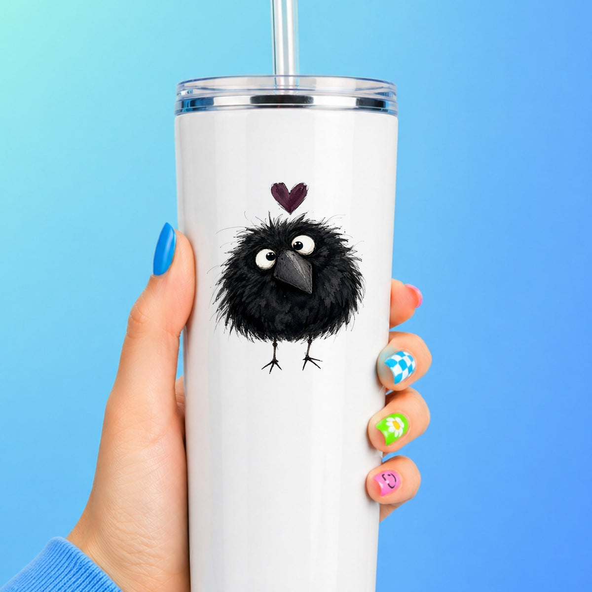 Fluffy Black Crow UV DTF sticker applied to a white straw tumbler on a blue background