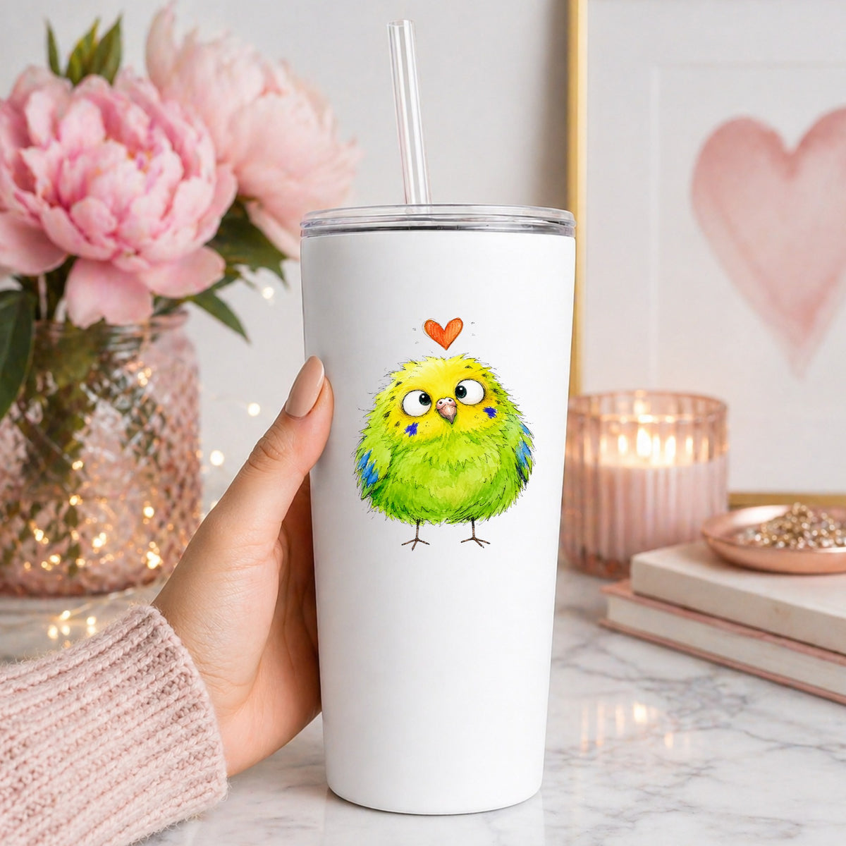 Funny Green Budgie UV DTF sticker applied to a white straw tumbler beside pink peonies