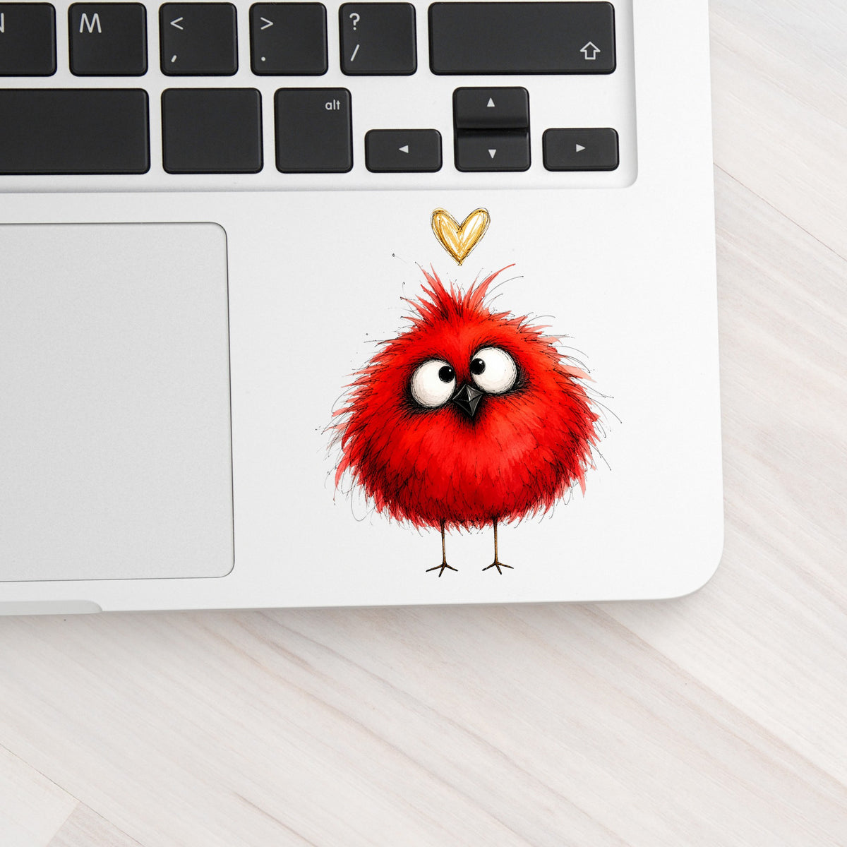 Funny Red Cardinal UV DTF sticker applied to a silver laptop beside the keyboard