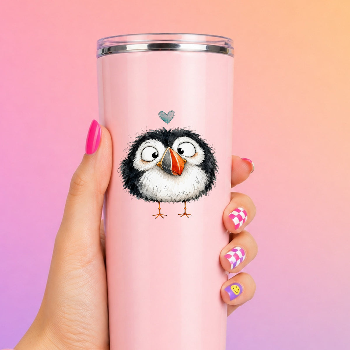 Cartoon Puffin UV DTF sticker applied to a tall pink tumbler on a pink and orange background