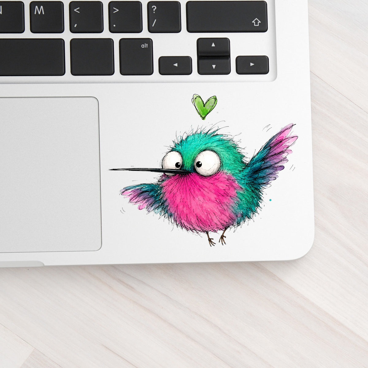 Flying Cartoon Hummingbird UV DTF sticker applied to a silver laptop beside the keyboard