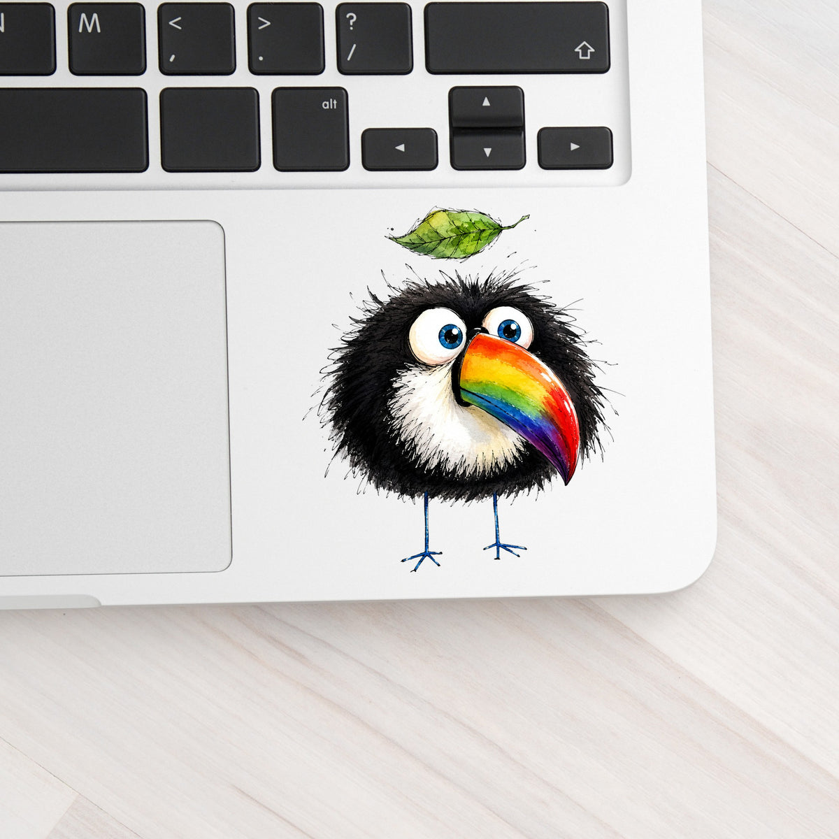 Toucan With Leaf UV DTF sticker applied to a silver laptop beside the keyboard