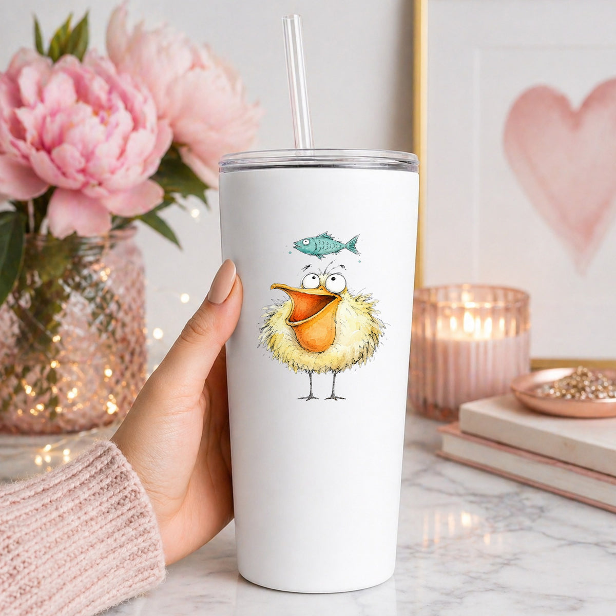 Funny Pelican With Fish UV DTF sticker applied to a white straw tumbler beside pink peonies