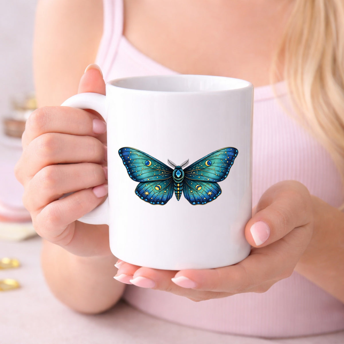 Teal Celestial Moth UV DTF sticker applied to a white coffee mug held in both hands