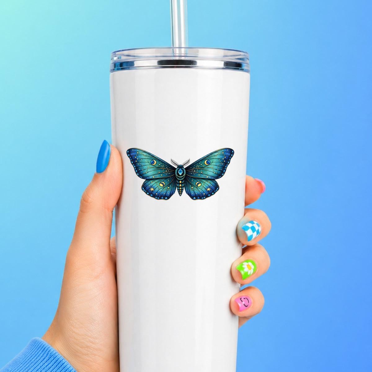 Teal Celestial Moth UV DTF sticker applied to a white straw tumbler on a blue background