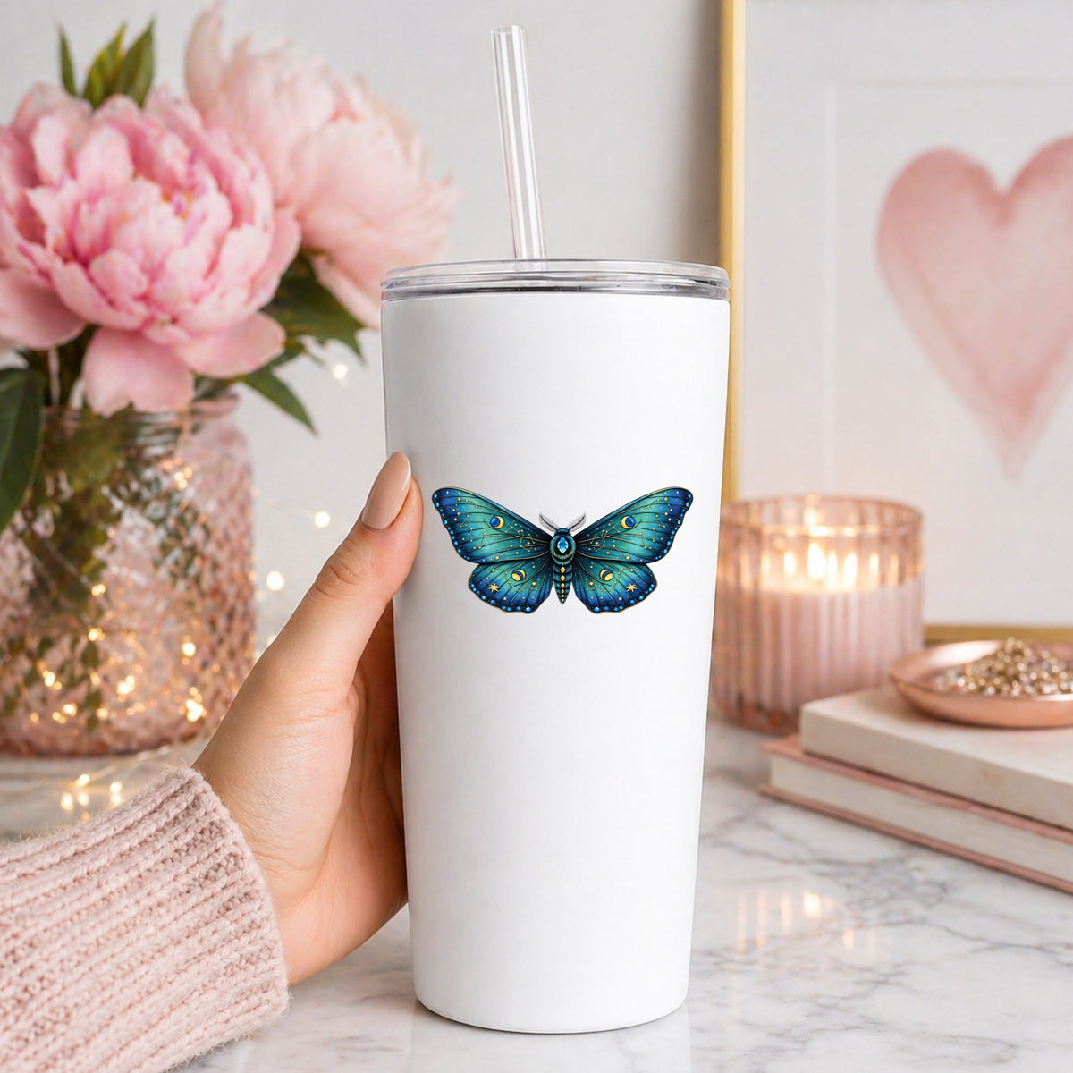 Teal Celestial Moth UV DTF sticker applied to a white straw tumbler beside pink peonies