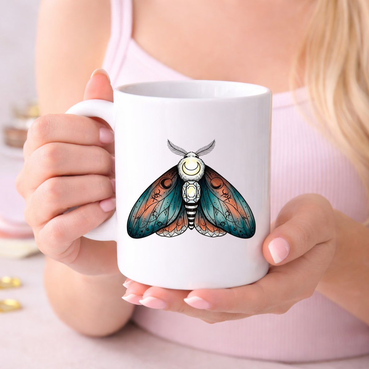 Coral Teal Crescent Moon Moth UV DTF sticker applied to a white coffee mug held in both hands
