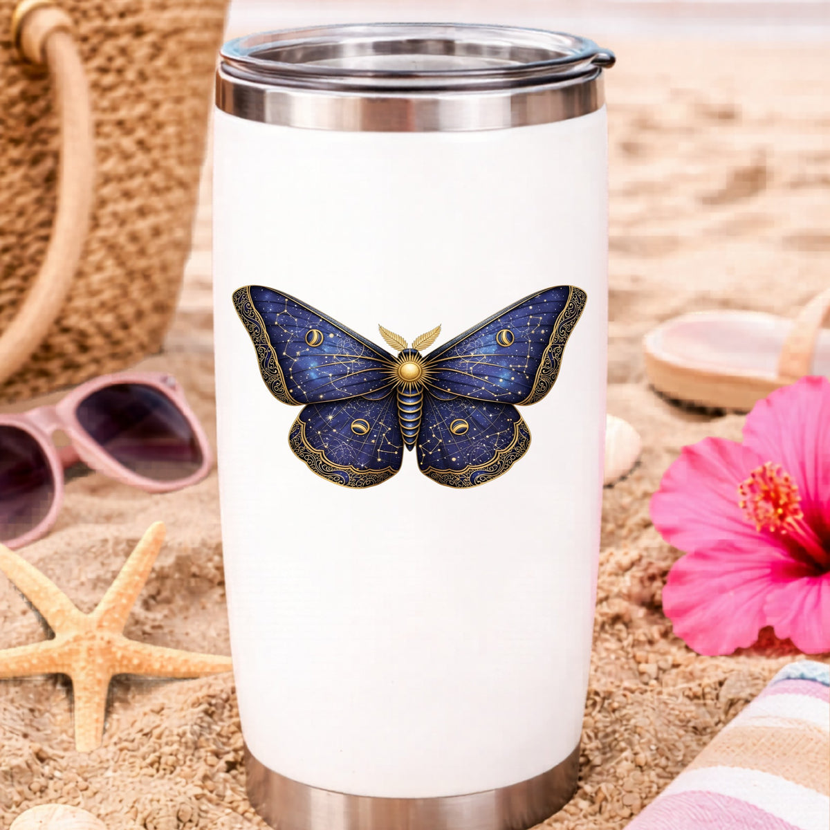 Navy Constellation Moth UV DTF sticker applied to a white travel tumbler on beach sand