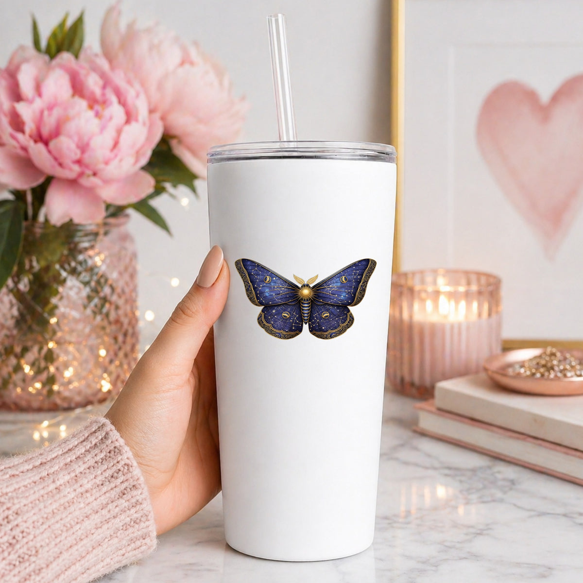 Navy Constellation Moth UV DTF sticker applied to a white straw tumbler beside pink peonies