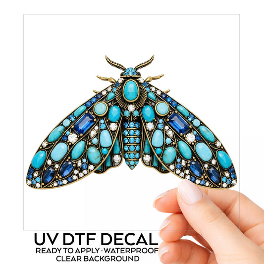 Turquoise Jeweled Moth UV DTF sticker on its backing card, held in hand