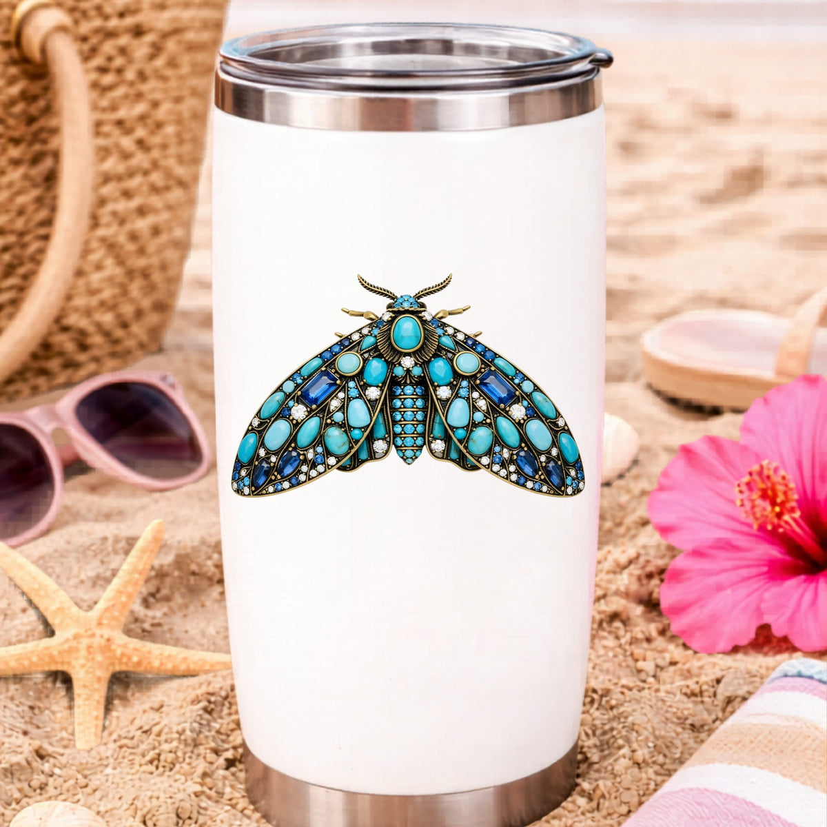 Turquoise Jeweled Moth UV DTF sticker applied to a white travel tumbler on beach sand