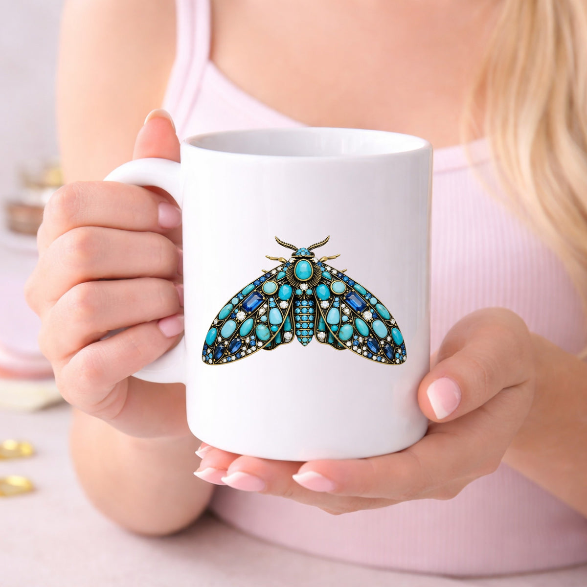 Turquoise Jeweled Moth UV DTF sticker applied to a white coffee mug held in both hands