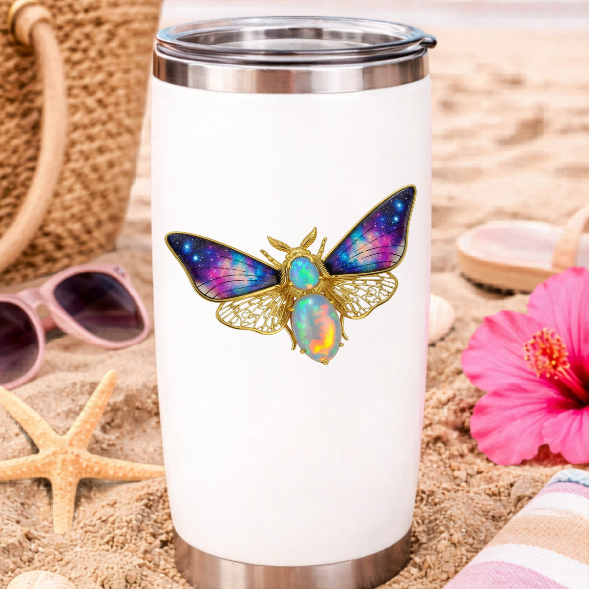 Opal Galaxy Moth UV DTF sticker applied to a white travel tumbler on beach sand