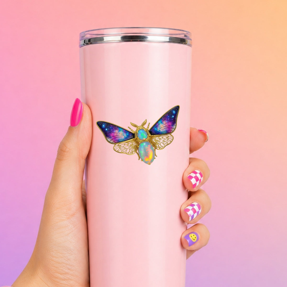 Opal Galaxy Moth UV DTF sticker applied to a tall pink tumbler on a pink and orange background
