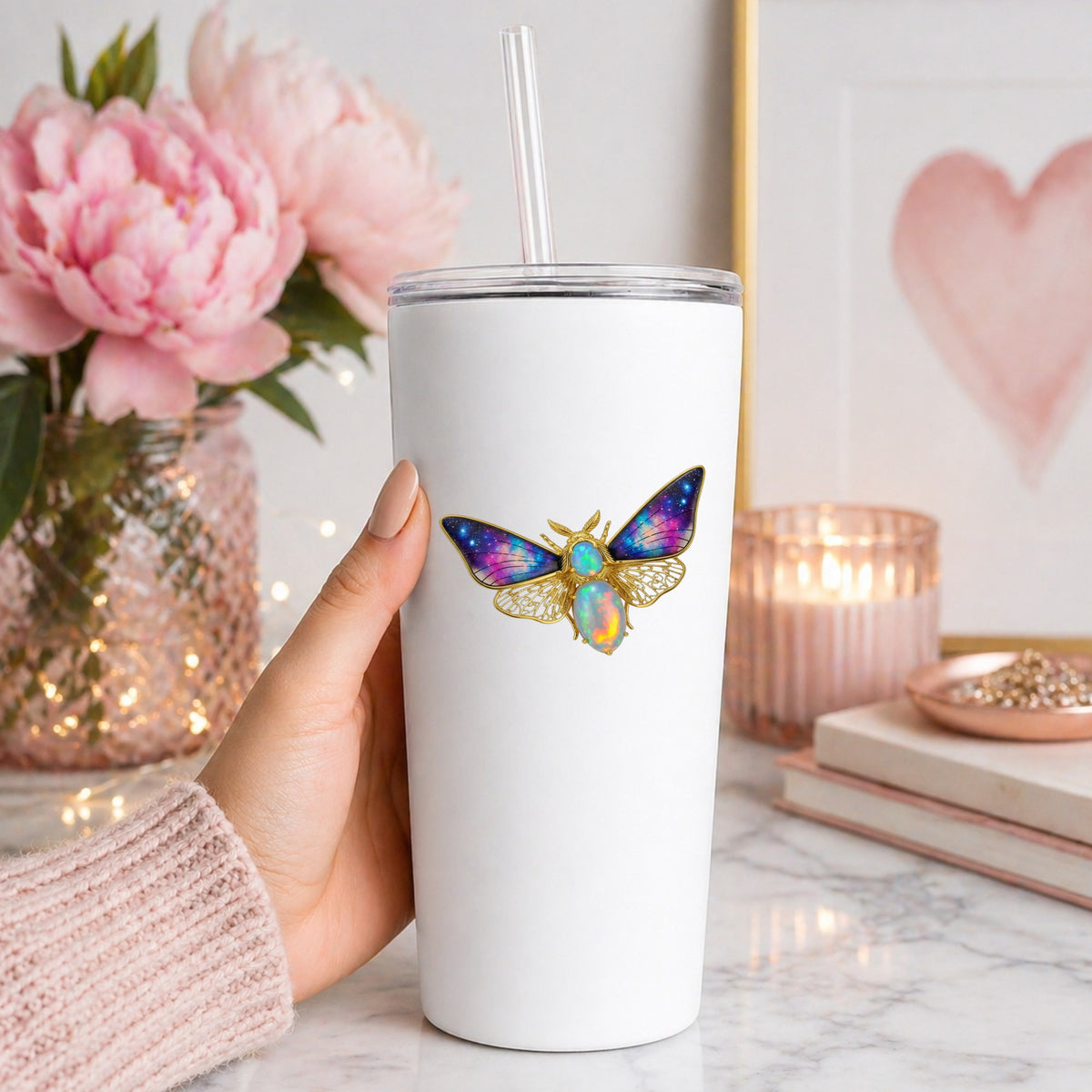 Opal Galaxy Moth UV DTF sticker applied to a white straw tumbler beside pink peonies
